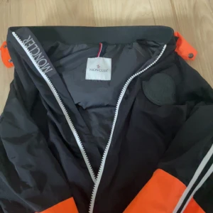 Svart och orange jacka från Moncler - Snygg svart och orange jacka från Moncler med ett svart märke på bröstet. Dragkedjan är en Moncler märke och den är i jätte bra skick , pris diskuteras 