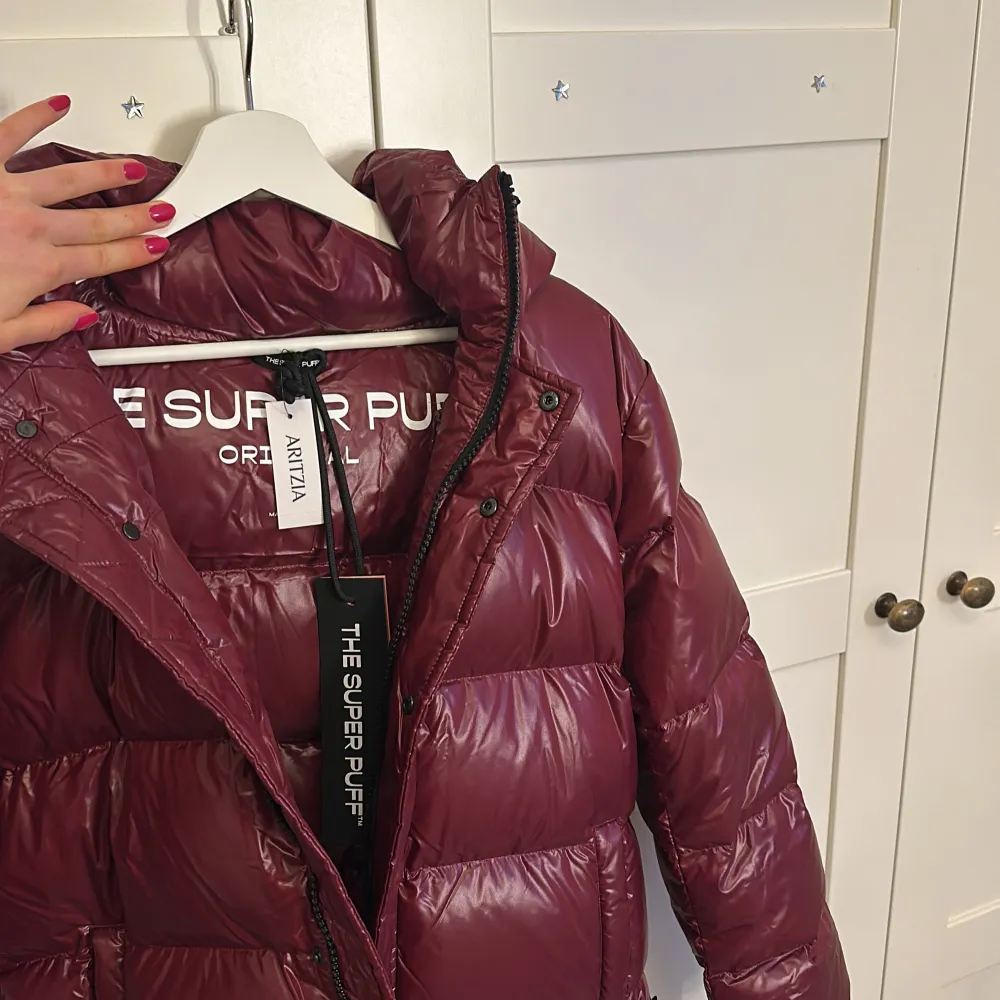 Säljer ny vinröd glansig pufferjacka i fransk taft från Aritzia. HELT OANVÄND MED ALLA LAPPAR OCH KARTONG!! Hög krage och långa ärmar, perfekt för kyliga dagar. Den är både stilren och funktionell med en modern look. Fraktad från USA. Köptes december 2024, säljs inte längre. Superfin kvalitet😍😍. Takit.
