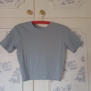 Ljusblå t-shirt från 157 - Säljer en ljusblå t-shirt från 157 i storlek M. T-shirten är tillverkad i bomull och elastan för en bekväm passform. Den har korta ärmar och en klassisk rund halsringning. Perfekt för en avslappnad stil.