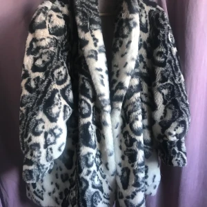 Svartvit pälsjacka med snöleopardmönster - Säljer en majestätisk fuskpälsjacka med snöleopardmönster. Jackan har en oversized passform och är i vintage estetik. Den har  ärmar som är rymliga och är lätt klockad nertill. Väldigt cruella duville. Väldigt bratig. Jag är small och 176 men burit denna, men egentliga storlek är L enligt etikett.