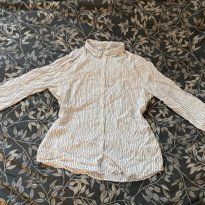 Randig skjorta från KappAhl - Säljer en stilren vit och svart randig skjorta från KappAhl. Skjortan har långa ärmar och knappar framtill med tunnt material. Lite skrynklig men övrigt inga defekter!🌸