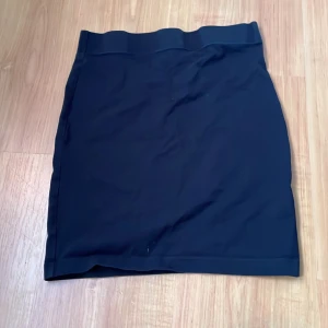 Svart kjol - Snygg svart kjol i enkel design. Perfekt för en stilren look. Kjolen har en rak passform och är knälång, vilket gör den mångsidig och lätt att matcha med olika toppar.