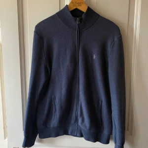 Ralph Lauren full-zip - Säljer en stilren marinblå tröja från Ralph Lauren i pima bomull. Tröjan har en dragkedja framtill och långa ärmar. Perfekt för en trendig look. Snygg o billig full-zip💯har vanligtvis storlek L och denna tröjan passar mig precis, men har vänner som använder storlek M som denna även passar för. Så passar både M och L i storleken 👍