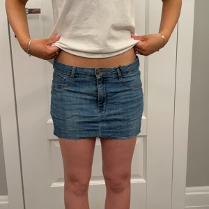 Blå jeanskjol - Snygg blå jeanskjol i kort modell med klassisk femficksdesign och knappstängning fram. Perfekt för en avslappnad stil. Midjemått: 80cm