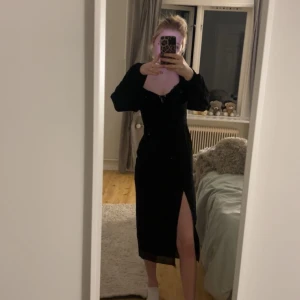 Svart klänning med slits -  svart klänning med lång ärm och en slits. Klänningen har en v-ringad design med snörning vid bysten och en öppen rygg. Jätte fin men har endast kommit till användning 1 gång sedan den köptes. Den är köpt på Gina tricot för ungefär 2 år sedan. 😍🙏🏻 