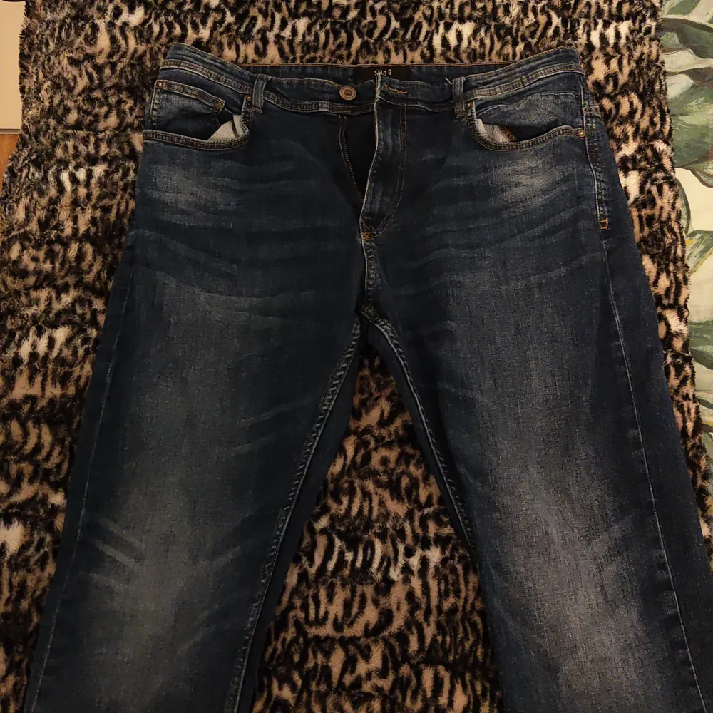 Snygga mörkblå jeans från Smog med klassisk femficksdesign och knappgylf. Jeansen har en lätt tvättad look och är perfekta för en avslappnad stil. Tillverkade i Bangladesh.. Farkut & Housut.