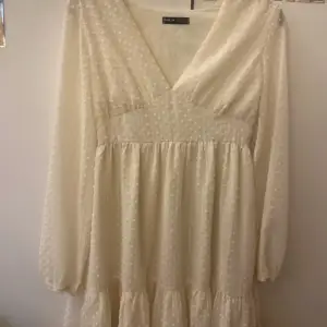 Säljer en söt vit klänning från Shein med prickigt mönster och v-ringning. Klänningen har långa ärmar och en dragkedja i sidan för enkel påklädning. Perfekt för en somrig look! 🌼