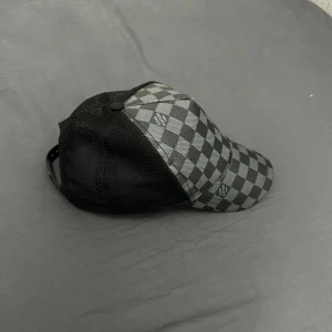 Rutig keps med nätpaneler L*V - Snygg keps med svart och grått rutmönster och nätpaneler på sidorna för extra ventilation. Perfekt för en avslappnad stil.