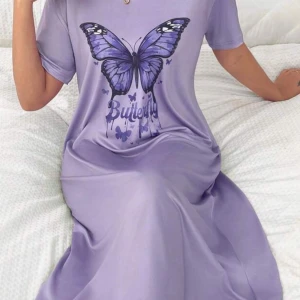 Lila klänning med fjärilstryck - Säljer en lila klänning med ett stort fjärilstryck på framsidan. Klänningen har korta ärmar och en avslappnad passform, perfekt för en bekväm stil. Den är gjord i ett mjukt material som känns skönt mot huden.