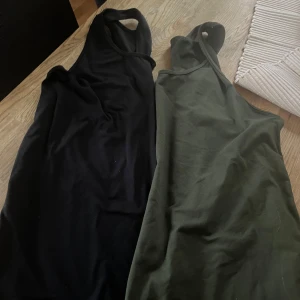 Ett grönt och ett svart  linne  från Newbody - Säljer två  linnetoppar  från Newbody. Perfekt för träning eller en avslappnad dag. Toppen är ärmlös och har en enkel design som gör den lätt att matcha med andra plagg.
