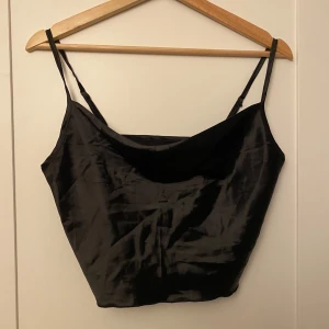 Svart sidenlinne - Svart sidenlinne med smala axelband och en mjuk, glansig yta. 