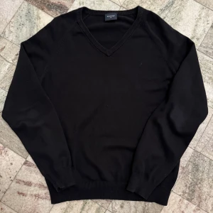 Svart v-ringad tröja från Boomerang - Säljer en stilren svart tröja från Boomerang i storlek M. Tröjan är v-ringad och har långa ärmar. Den är tillverkad av en mjuk bomullsblandning med nylon och lycra för extra komfort. Perfekt för en klassisk look.