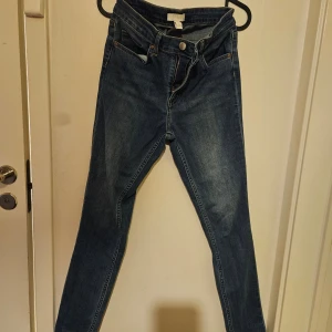 Blå jeans med hög midja - Snygga blå jeans med hög midja och skinny passform. Klassisk femficksdesign med knapp och dragkedja framtill. Perfekta för en stilren look.