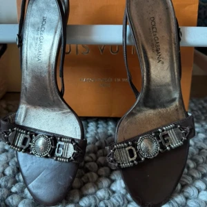 Kitten heels  från Dolce & Gabbana - Eleganta bruna klackar från Dolce & Gabbana med dekorativa pärlor och logotypdetaljer på remmen. 