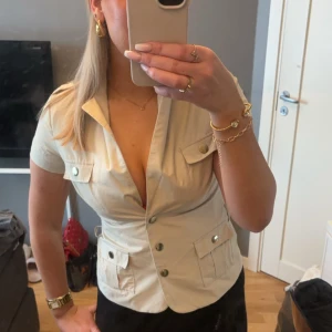 Beige kortärmad kavaj - Snygg beige kavaj med korta ärmar och knappar framtill. Oanvänd.