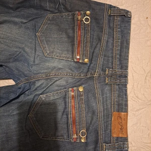 Blå jeans från Esprit - Snygga blå jeans från Esprit med unika detaljer som broderade fickor och metallringar. Lågmidjade och passar S/Xs och längd runt 165. Köpt på second hand men i bra skick.