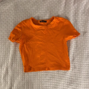 Orange croppad t-shirt från Zara - Säljer en snygg orange croppad t-shirt från Zara. Det står att den är i storlek M men då är det nog menat för att den ska vara croppad. Annars passar den nog 134-140 i barnstorlek 🫶💕