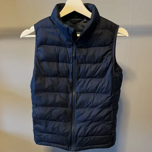 Mörkblå dunväst från Uniqlo - Tjena säljer min uniqlo väst i färgen mörkblå. Storleken är 11-12 år gammal och fits folk som är 155 cm långa. Inga skador eller hål. Hör av dig vid minsta frågan😀