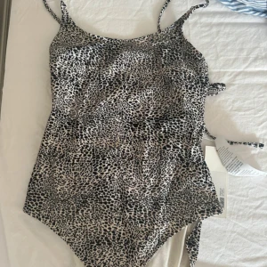 Leopardmönstrad baddräkt från Arket - Snygg leopardmönstrad baddräkt från Arket med smala axelband. Perfekt för en dag på stranden eller vid poolen. Trendig och bekväm design. Storlek 36