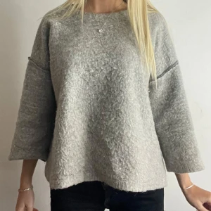 Grå tröja med trekvartsärm - Mysig grå tröja med trekvartsärm och en lös passform. Perfekt för kyligare dagar med sitt fluffiga material. Tryck köp nu💌