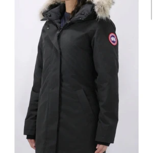 Canada Goose vinterjacka - Säljer en stilren svart parkajacka från Canada Goose med pälsdetalj på huvan, modellen heter Parka Victoria . Jackan har en medellång passform och är perfekt för kalla vinterdagar. Endast använt 2 vintrar och är i nyskick. Storlek XS passar S. Behöver sälja akut!!