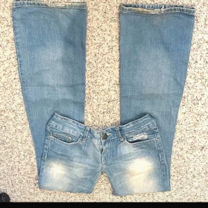 Blå bootcut jeans med broderade detaljer - Snygga blå bootcut jeans med broderade detaljer på bakfickorna. Lågmidjade. Lite slitna nere vid fötterna.