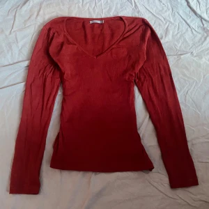 Röd långärmad tröja med v-ringning - Säljer en stilren röd tröja med v-ringning och långa ärmar. Perfekt för en avslappnad look. Tröjan är i storlek L och har en smickrande passform eftersom att jag har sytt in den. På sidan har dock sömmen gått upp ( bild 5 ). Dock inget som märks.❤️