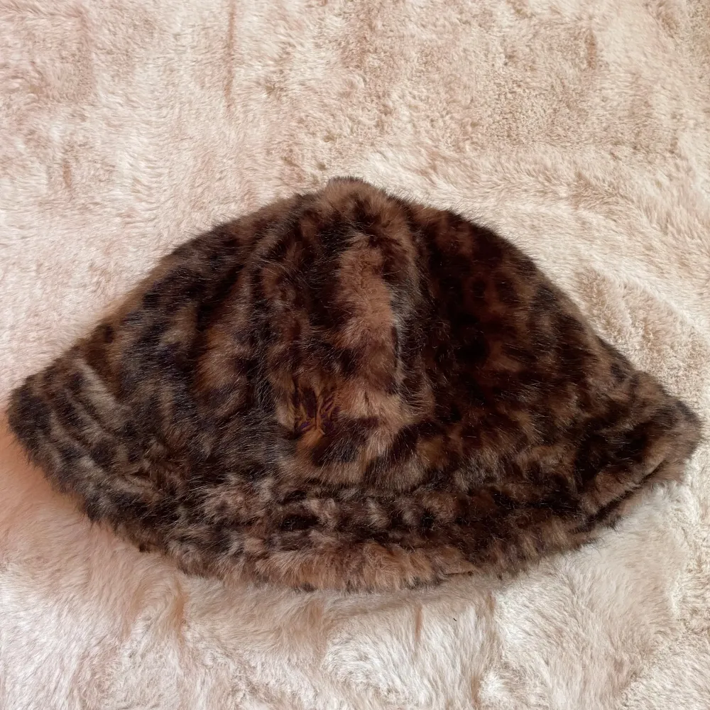 Snygg leopardmönstrad hatt från Needles i ett mjukt och fluffigt material. Hatten har en liten tofs på toppen och ett lila broderat emblem på sidan med märket Needles. Köpt två år seden för 2600kr. Använt den tre gånger ute efter inköp, sedan har den bara varit en del av min samling, då jag inte känner att den klär mig. Priset kan diskutera :). Asusteet.