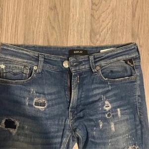 Blå jeans från Replay - Snygga blå jeans från Replay med slitna detaljer och en klassisk femficksdesign. De har en dragkedja och knapp framtill. Perfekta för en avslappnad stil.