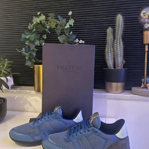 Valentino rockrunner  - Snygga blå sneakers från Valentino med en stilren design. Skorna har en kombination av mocka och syntetmaterial, vilket ger dem en unik look. De har snörning och en kontrasterande vit häl. Perfekta för en trendig stil.