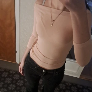 Beige offshoulder topp från Dakota - Säljer en stilren beige offshoulder topp från Dakota. Toppen har en tight passform, perfekt för en elegant look. Tillverkad i Italien och skön material 