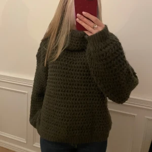 Mörkgrön stickad tröja - Mysig mörkgrön stickad tröja med en lös passform och långa ärmar. 