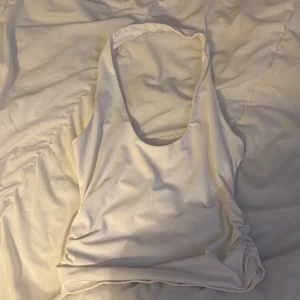 Vit ärmlös linnetopp - Säljer en stilren vit ärmlös linnetopp med djup urringning. Perfekt för varma sommardagar eller som ett basplagg i garderoben.