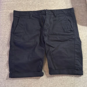 Mörkblå shorts från William Baxter - Snygga mörkblå shorts från William Baxter med uppvikta ben och dragkedja. Perfekta för en stilren look.