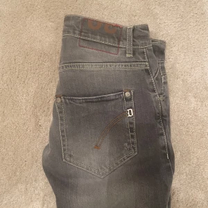 Dondup Jeans - Snygga grå jeans med en slim passform och klassisk femficksdesign. Byxorna har en diskret tvättad look och är perfekta för en stilren vardagsoutfit. De har dragkedja och knapp i midjan.