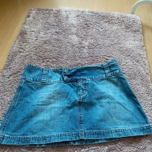 Blå kort jeanskjol från JAM - Snygg blå jeanskjol från JAM med knapp- och dragkedjeförslutning. Perfekt för en avslappnad stil. Kjolen har en klassisk design med bälteshällor och en kort längd.