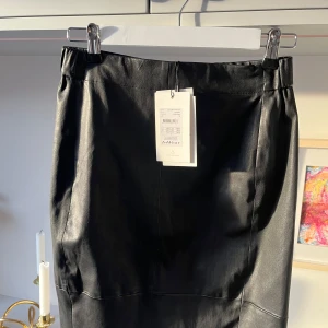 Svart oanvänd skinnkjol från InWear - Snygg svart skinnkjol från InWear i modellen Luella Skirt Premium. Kjolen har en elegant och stilren design, perfekt för att lyfta vilken outfit som helst. Tillverkad i äkta läder för en lyxig känsla. Nypris 2000 kr. Hör av dig om du har några eventuella frågor!