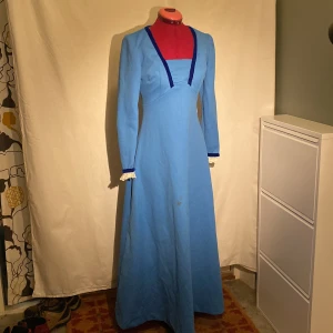 Blå långklänning - Blå långklänning med mörkblå sammetsdetaljer och spets vid ärmsluten. Hemsydd av någon dam som förmodligen såg fantastisk ut. Älskar denna klänning något enormt men har en liknande och behövde göra mig av med en av dem ): Har en liten förslitningsskada vid ena axeln och en liten fläck på kjolen som fanns när jag köpte den. Lång dragkedja i ryggen, går som smör. Skulle säga stl S-M