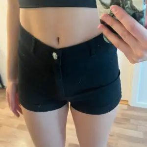 Säljer ett par svarta shorts i nyskick. De är tighta och lågmidjade med knapp och dragkedja framtill. Perfekta för sommaren eller en utekväll. Passar bra till både vardag och fest!