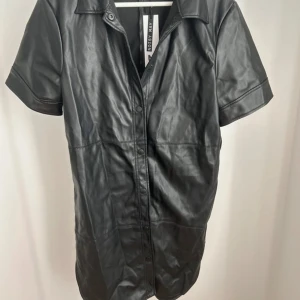 Pu läder klänning  - Ingår ett knyt band i samma material kom ej med på bild. Stretchigt material 