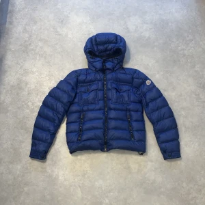 Blå dunjacka från Moncler - Säljer en snygg blå dunjacka från Moncler. Den är i extremt bra skick och modellen heter Edward giubotto, strl 2, passar perfekt nu till vintern, hör av er vid minsta fundering, priset kan diskuteras.