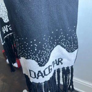 Svart och vit halsduk från Dagmar - Snygg och stilren svart och vit halsduk från Dagmar. Den har ett coolt mönster med små prickar och fransar i ändarna. Perfekt för att hålla sig varm under kyliga dagar. Passar både till vardags och festliga tillfällen.