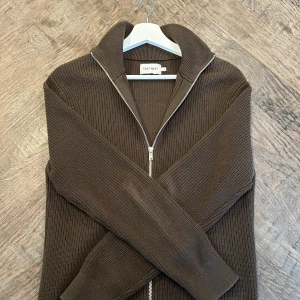 East west full-zip - Säljer denna full zip ifrån East west! Aldrig använd! Storlek S. Köpt för 899 på brothers!Hör av er vid minsta fråga!