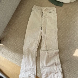 Beige manchesterbyxor från H&M - Säljer ett par snygga beige manchesterbyxor från H&M. De är i en skön och mjuk manchesterkvalitet, perfekt för höst och vinter. Byxorna har en rak passform och är midwaist, vilket gör dem både bekväma och stiliga. Perfekta för en avslappnad men ändå trendig look!