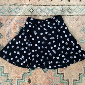 Svart blommig sommarkjol - Fin sommarkjol i storlek XS. Använd några få gånger för längesedan!  OBS! Står ej för frakt 