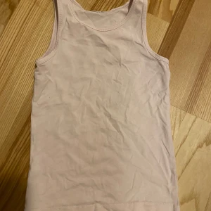 Baslinne - Väldigt ljust rosa linne. Lappar bortklippta. Jag uppskattar denna till storlek 130. Flitigt använd men har mycket kvar att ge!  Kolla in mina övriga annonser för samfrakt! 