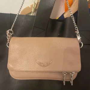 Zadig & Voltaire väska - Jätte bra skick använt några gånger. Har både det lilla och det stora bandet. Det saknas en diamant eller vad det är på Zadig märket där framme på väskan.