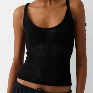 Svart stickad linnetopp från Bershka - Säljer en svart stickad linnetopp från Bershka. Toppen är ärmlös och har en tight passform, perfekt för sommaren. Den är gjord i ett luftigt stickat material som gör den både bekväm och stilren. Helt ny men säljer då den inte passade mig och var för sen med att lämna tillbaka 