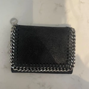 Stella Mcartney plånbok - Fin plånbok från Stella Mcartney i svart. Väldigt bra skick förutom en fläck på baksidan, se sista bilden!