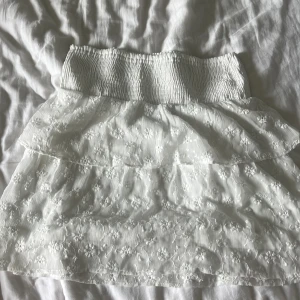 Blommig vit volang kjol - Jätte fin vit variant kjol med ett Blom mönster  Den är knappt använd och i jätte bra skick💕